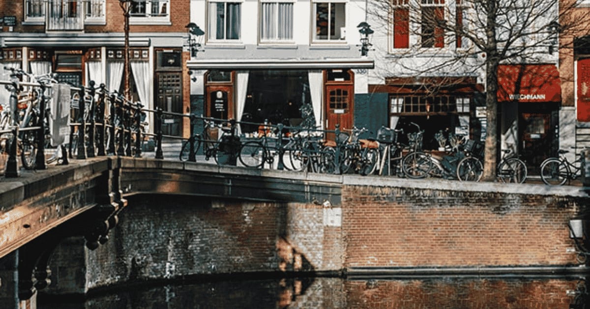 Bicycles along a canal bridge railing in front of the Wiechmann's red awning on the Prinsengracht