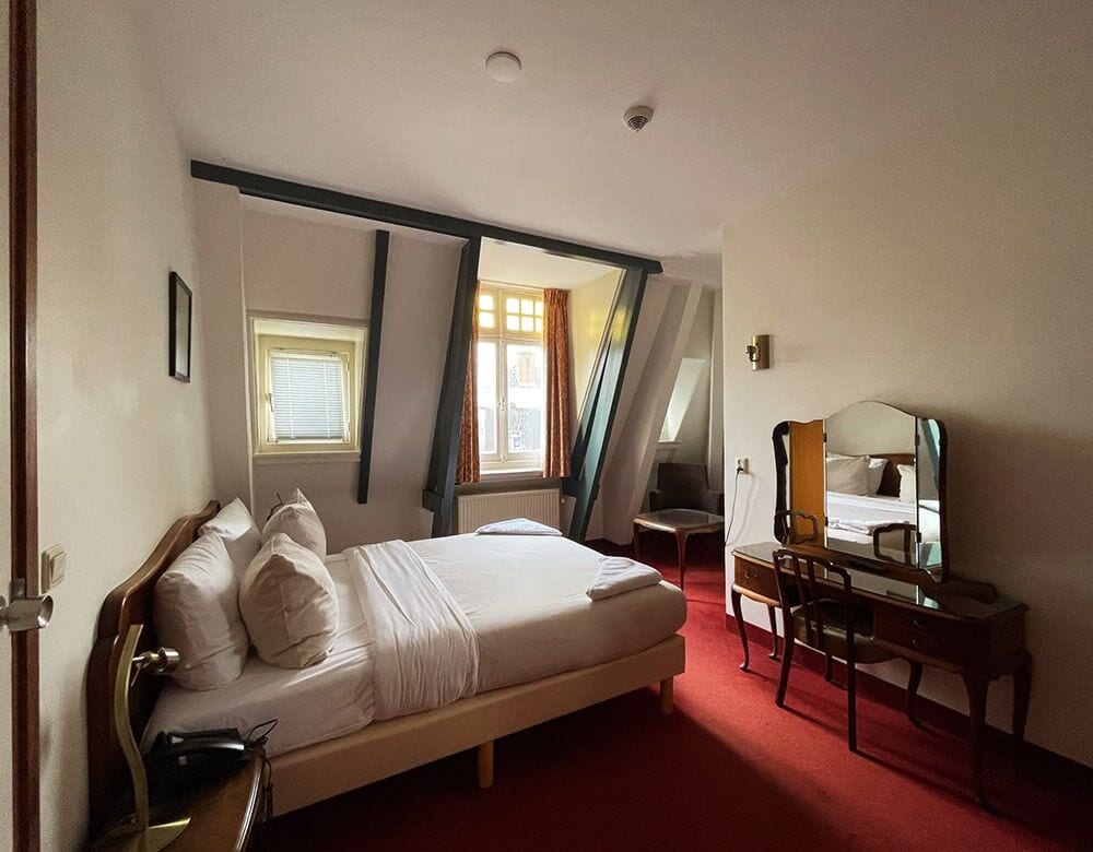 Double Loft Room with Canal View: exposed roof beams and a dormer window above the double bed