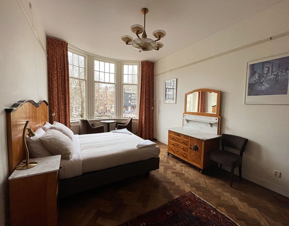 Family Suite: a bed and antique washstand beneath bay windows onto the canal