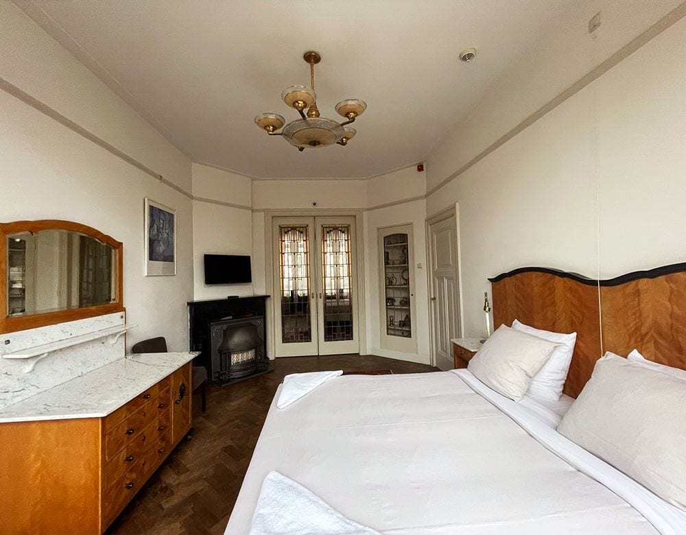 Family Suite: double bed, fireplace and French doors beneath a brass chandelier