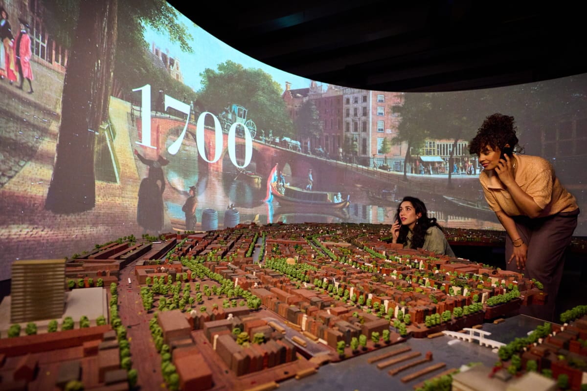 Visitors at the Grachtenmuseum's scale model of Amsterdam's canal ring, projected with the year 1700