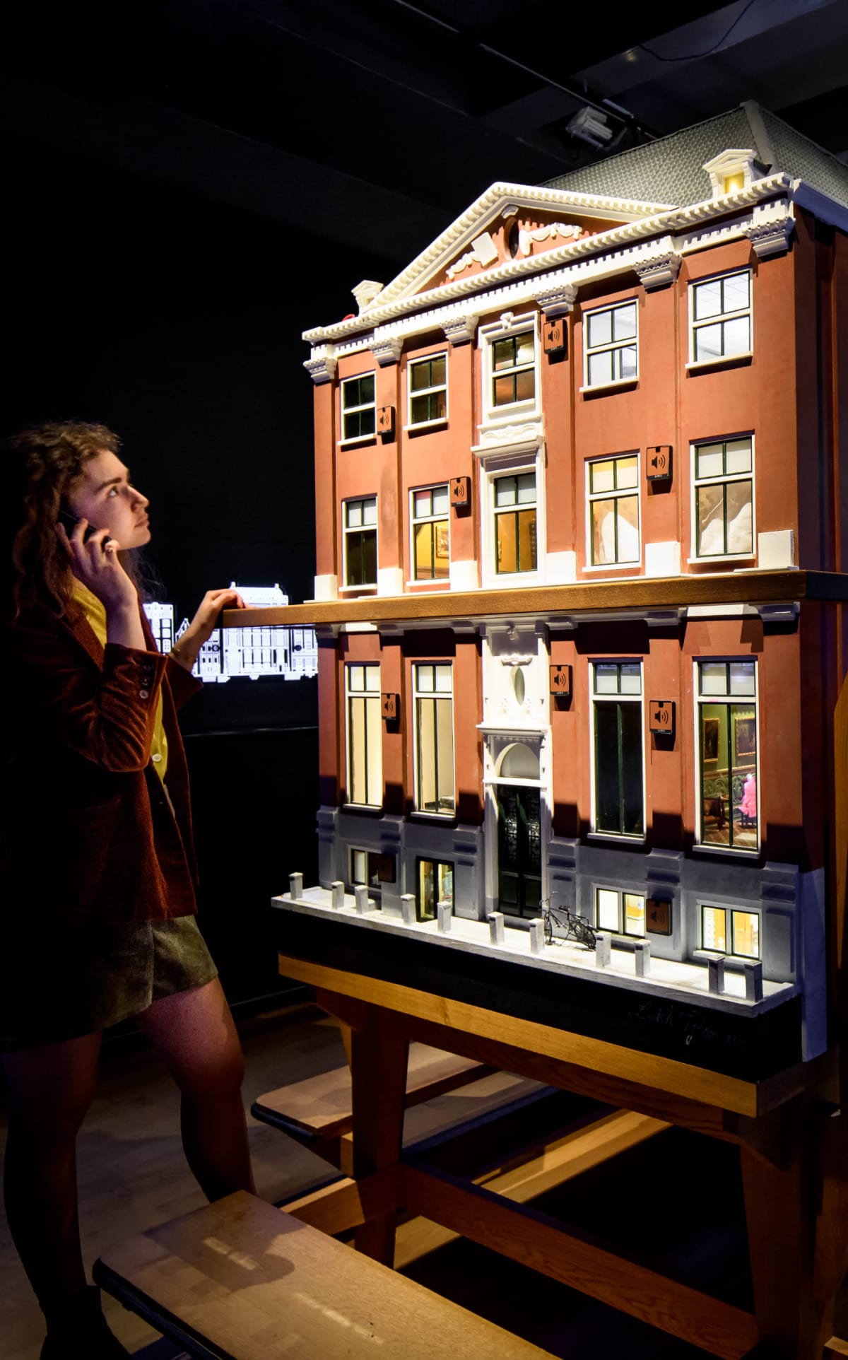 A visitor at the Grachtenmuseum's illuminated model of a canal house