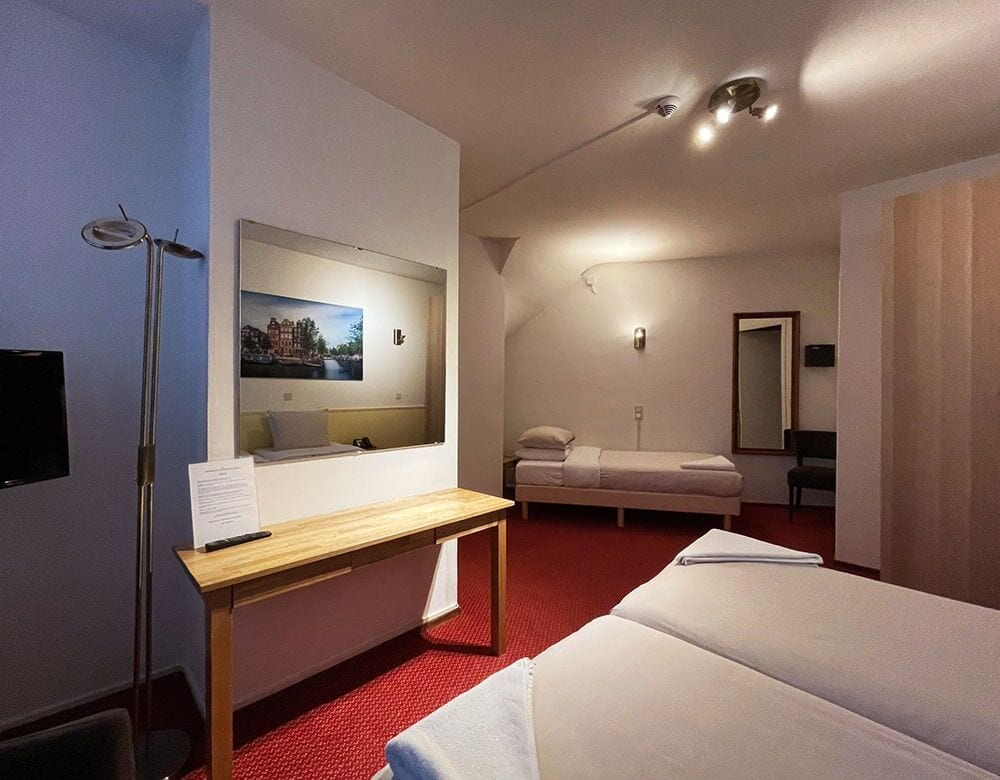 Triple Room: single beds, a desk and a wall-mounted television