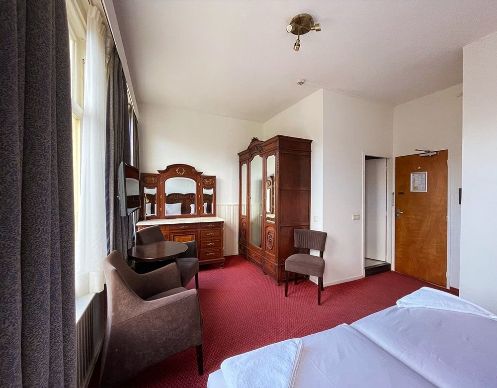 Twin Room with Canal View: an antique wardrobe and mirrored dresser, with armchairs by the window