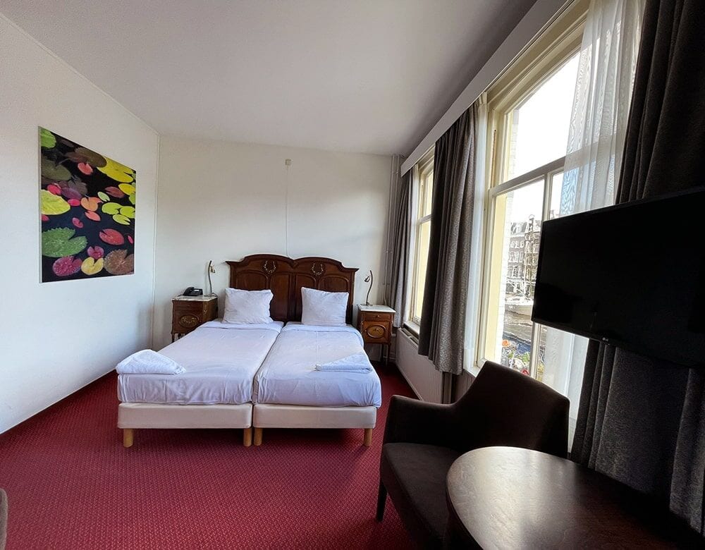 Twin Room with Canal View: two single beds beneath a colourful painting