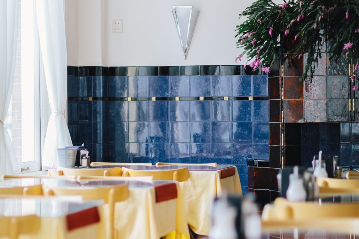 The hotel's breakfast room, tables laid with yellow linen beneath Delft blue tiles