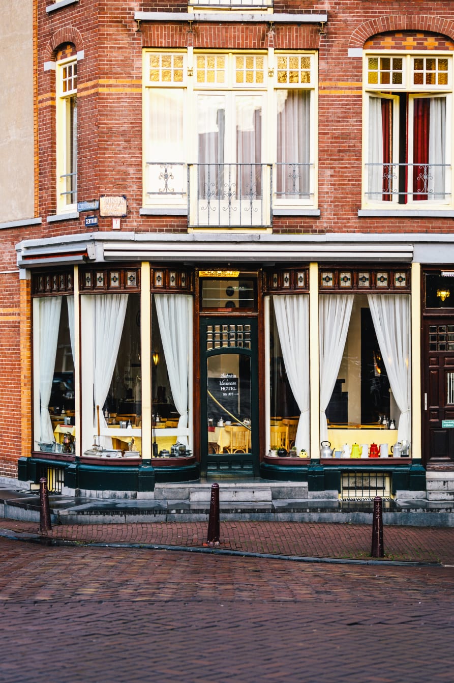 The Amsterdam Wiechmann Hotel's brick façade on the Prinsengracht, with curtained bay windows on the ground floor
